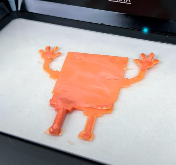 Orange character print on the UltraCraft Reflex build platform